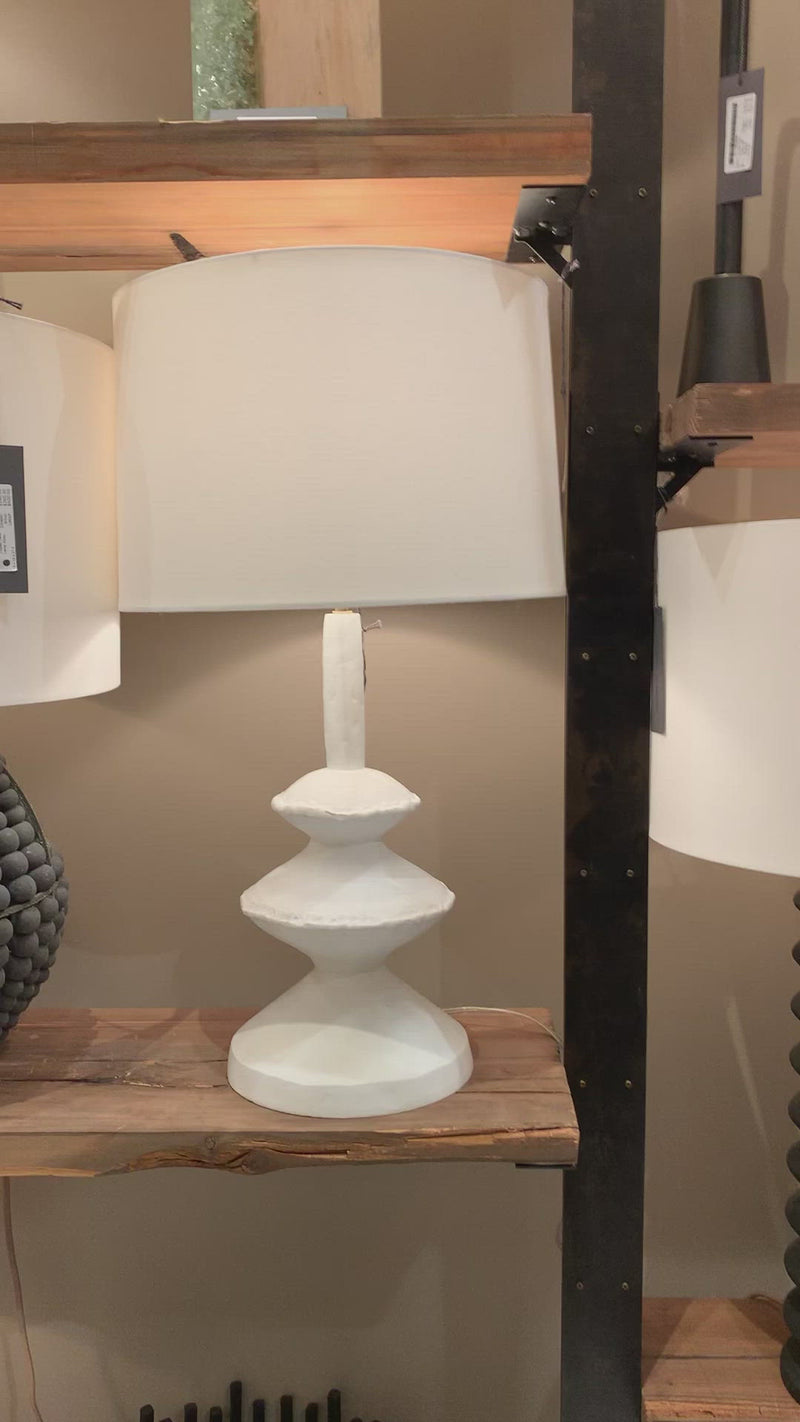 We love the unique base of this Hope Table Lamp. The matte white finish gives it clean look, completing the look for any living room, bedroom, or other space.   Size: 16"w x 16"d x 28"h  Shade Dims: 15 x 16 x 10.5